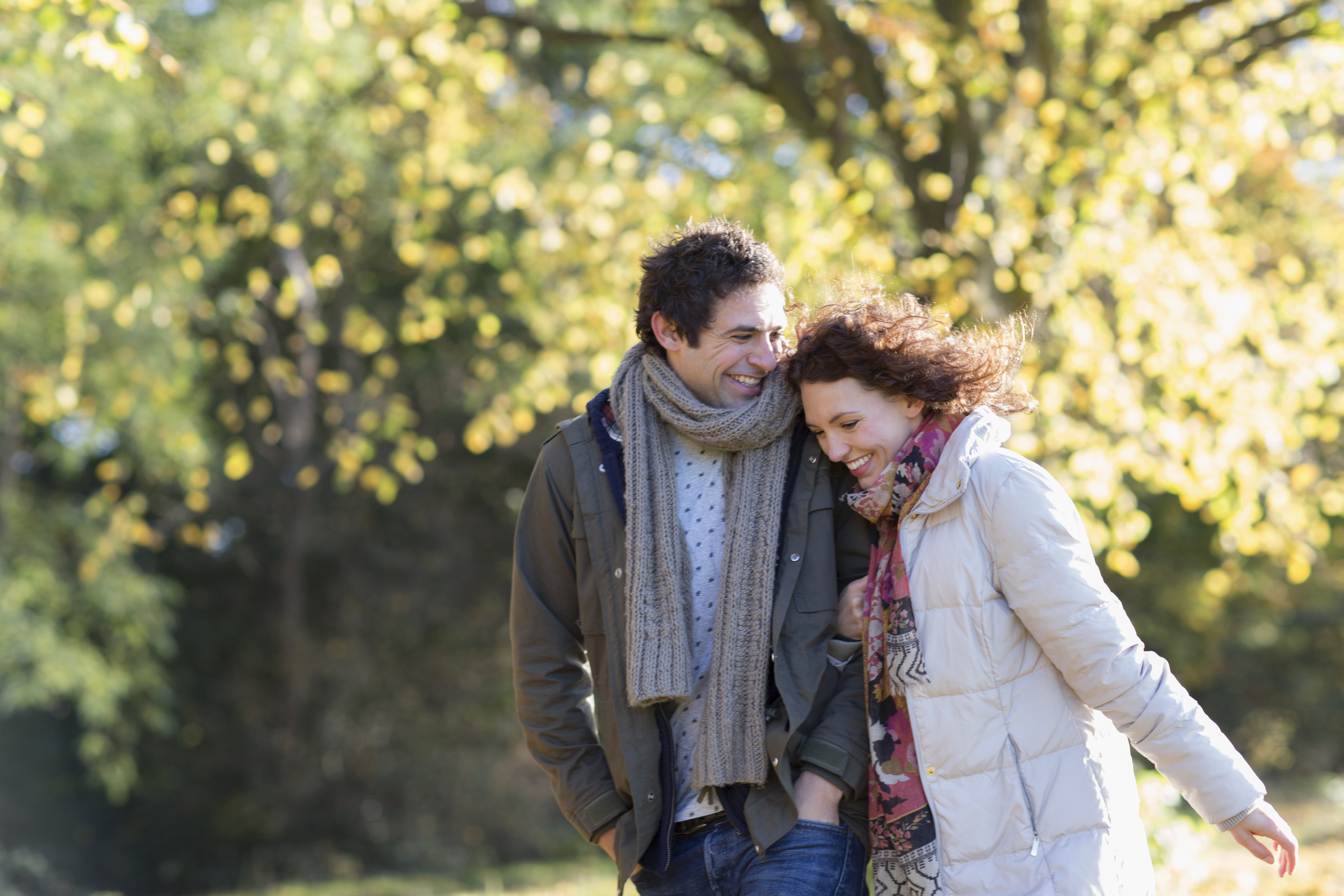 man and woman walking in park with linked arms