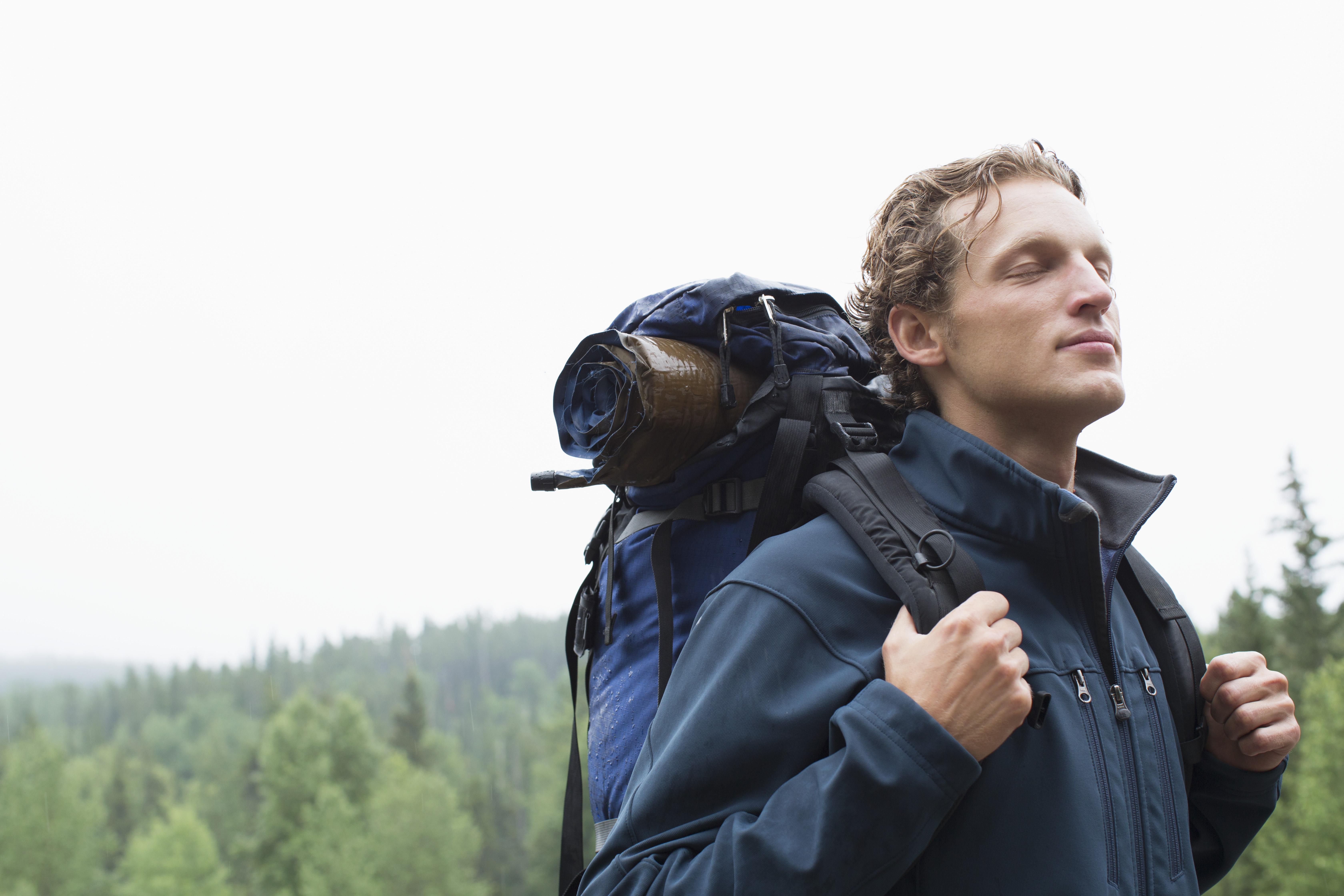 man with hiking backpack smiling in the rain